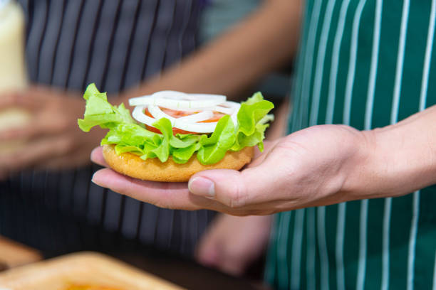 istock Chef preparing bread onion tomato vegetables and making hamburger in the kitchen. 1297054408