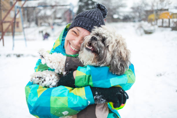 istock Senior woman playing with her dog outdoors on snow 1297060174