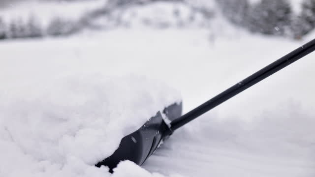 Teenage boy helping to remove snow from the backyard