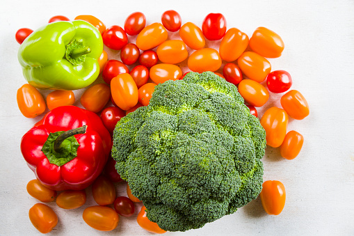 Cherry tomatoes, red and green bell pepper and broccoli on the white background, high angle view