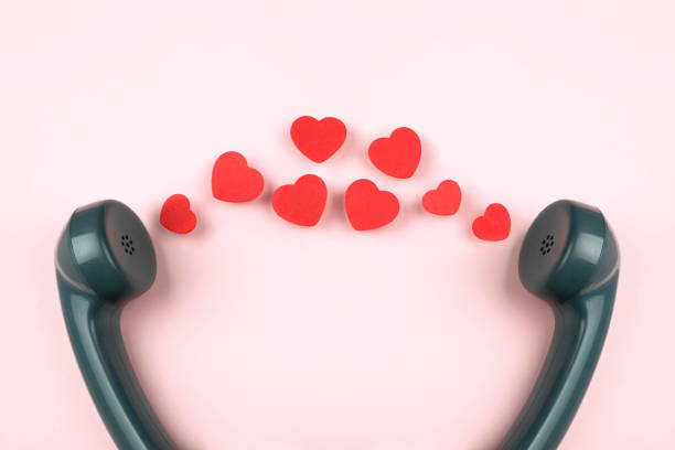 Old rotary telephone handset with red hearts    isolated on pink background