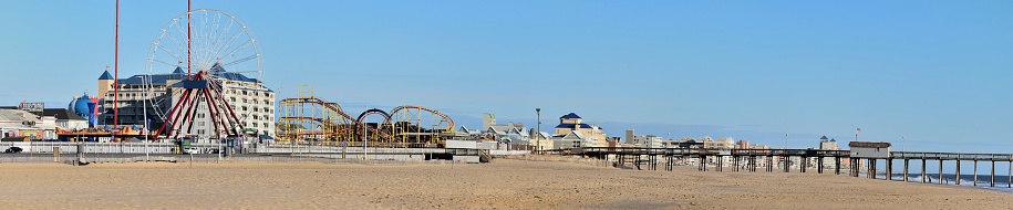 A clear blue sky, amusement park rides, fishing pier, deserted beach (almost) and boardwalk skyline in Ocean City, MD on a cold January morning