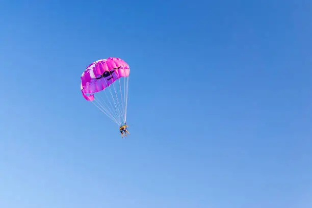 Photo of parasailing people under a parachute hanging in the air in summer. fun. feelings, family, travel, vacation. copyspace