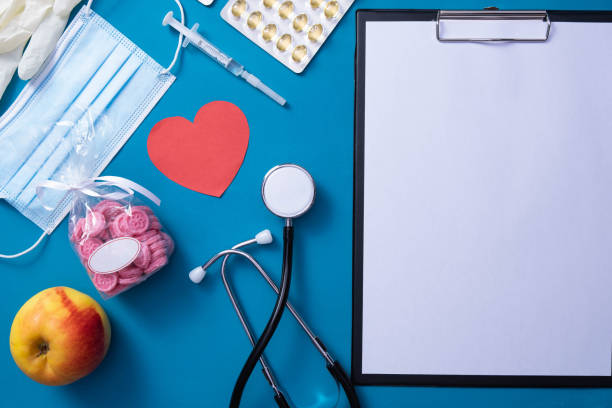 istock syringe, notepad, gloves, heart, apple, vitamins, pills, mask lie on the table, on a blue background 1297070055