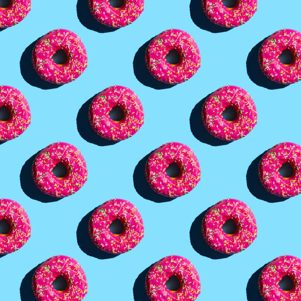 istock pattern of donuts in pink glaze sprinkled with colored crumbs on a blue background 1297070308