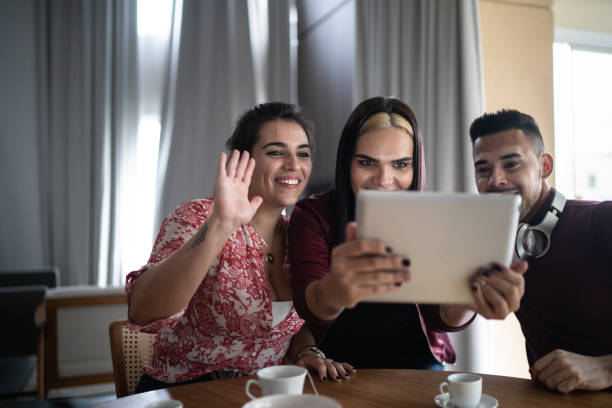 istock Friends together doing a video chat using digital tablet at home (including a transperson and vitiligo man) 1297076144