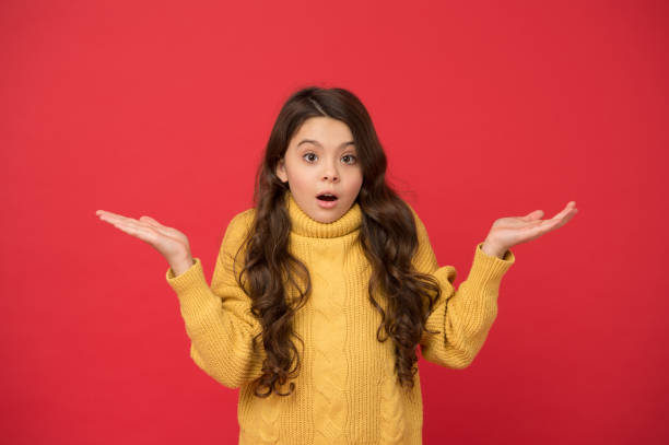 menina surpreso suéter de malha menina. moda para crianças. outono e roupas quentes de inverno. desgaste da estação quente. pequena beleza parede vermelha. menina bonita cabelo encaracolado longo. felicidade na infância.o que é uma surpresa - little girls autumn child red hair - fotografias e filmes do acervo