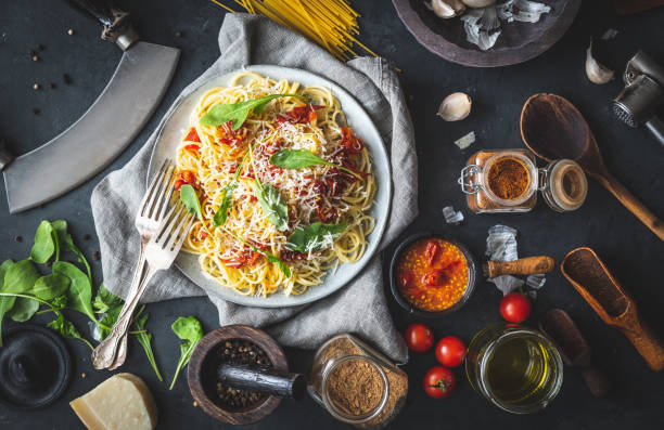 istock Italian dinner with pasta on ceramic plate with ingredients around on black background. Flat view. Top view. 1297078467