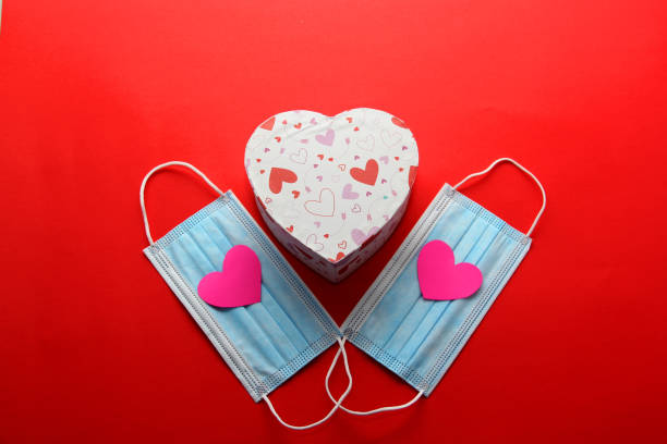 istock Tri-layer protection mask for clinical use with pink hearts on a red background 1297082464