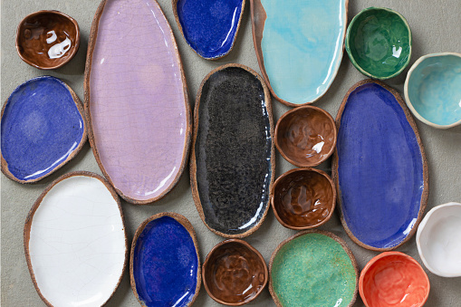 Handmade colorful ceramic empty dishes and plates background, top view. Collections of various small bowls