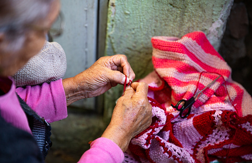 Old woman knitting at home in the evening.
