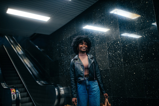 Young black woman with shopping bags posing in front of black background