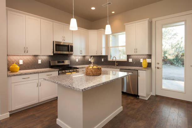 istock Modern Light and Bright Kitchen with Island, Dark Wood Floors, Grey Countertops, with White Cabinets 1297094965