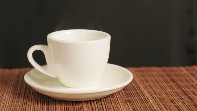 A woman puts a white fragrant coffee cup on the table.