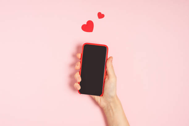 istock Woman's hands holding mobile phone with blank screen with heart shape 1297098788