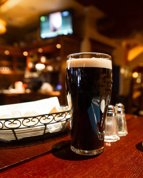 istock Glass of dark beer on a table in a pub setting 1297099160
