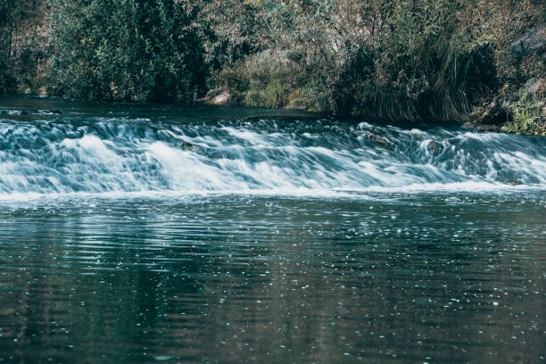 Wide river on summer day. Water flow on dam