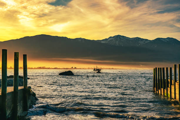 Fishing boat in Kaikoura bay as a sunset cloudscape closes over the coastal mountain range