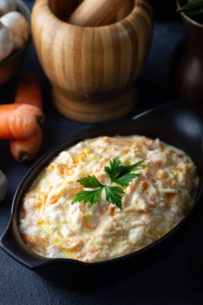 istock Carrot tarator in ceramic bowl with vegetable on dark background. Fresh carrot salad with garlic yogurt in bowl. 1297102944