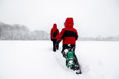 Mother and Son Snowshoeing Outdoors in Winter During Snowstorm (blizzard).