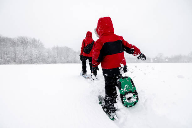 Mother and Son Snowshoeing Outdoors in Winter During Snowstorm Mother and Son Snowshoeing Outdoors in Winter During Snowstorm (blizzard). snowshoeing snow shoe red stock pictures, royalty-free photos & images