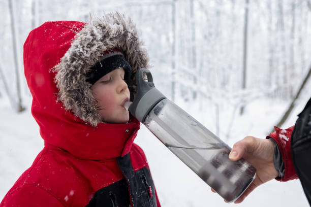istock Mother and Son Walking Outdoors in Winter During Snowstorm abd Drinking Water 1297104309