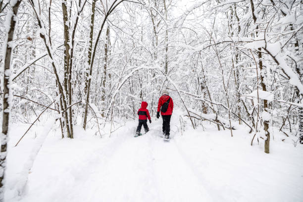 Mother and Son Snowshoeing Outdoors in Winter During Snowstorm Mother and Son Snowshoeing Outdoors in Winter During Snowstorm (blizzard). snowshoeing snow shoe red stock pictures, royalty-free photos & images