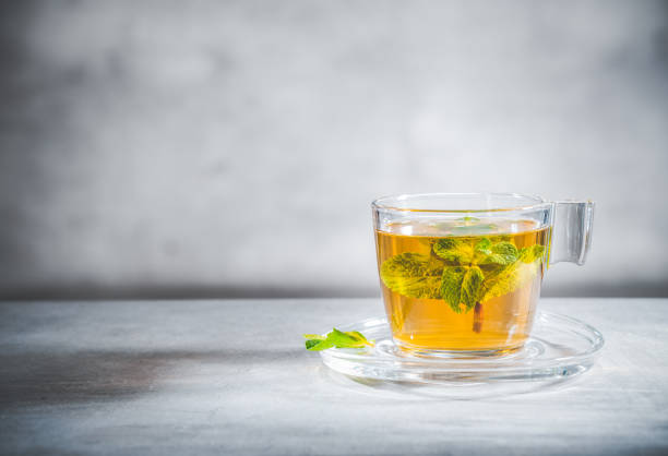 istock Mint tea with leaves in glass cup on gray background, front view 1297105153