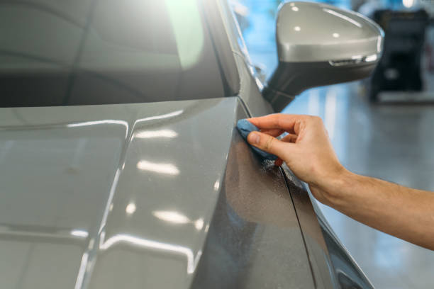 istock Worker hand clean car body with blue clay for cleaning before applying protective layer or coating to auto. Car detailing concept 1297105946