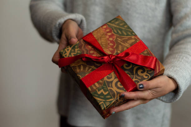 istock hands of a woman holding a gift box with a red bow. celebration concept 1297108821