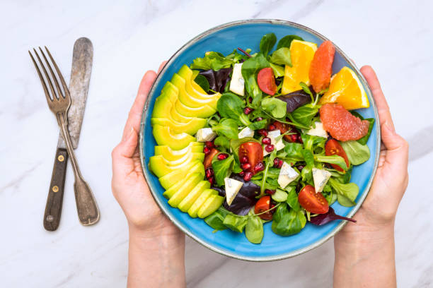 istock Vegetable salad bowl on table and female hands 1297109259