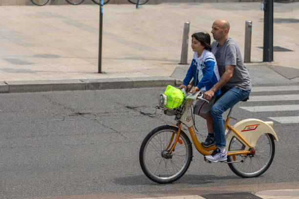 Streets of Milan / Milan / Italy - July 3, 2019: Father taking son to school by bicycle through the streets of Milan.