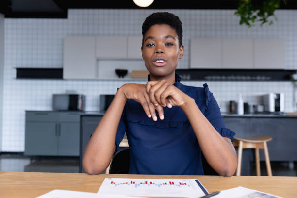 istock Mixed race businesswoman sitting having video chat going through paperwork in modern office 1297114791