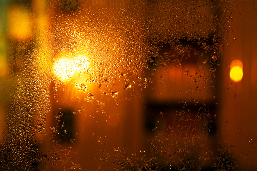 Melting ice on the window glass . Dim light in the winter