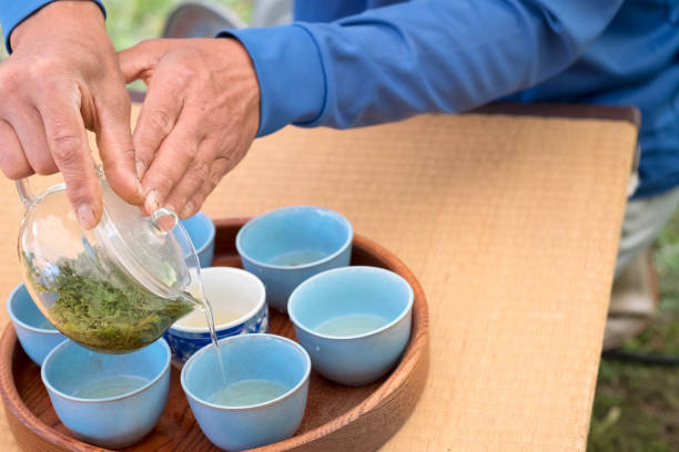 istock Japanese Man Pouring Green Tea for Guests in Back Yard 1297115799
