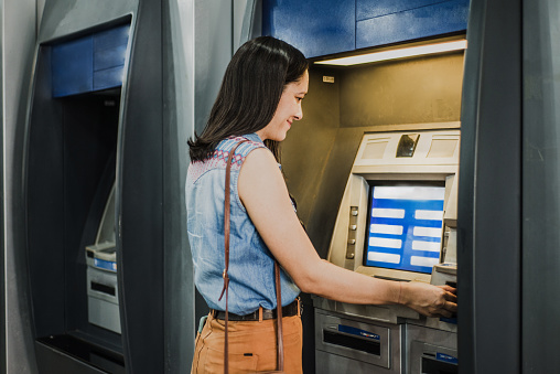 Woman using a money dispenser at the bank