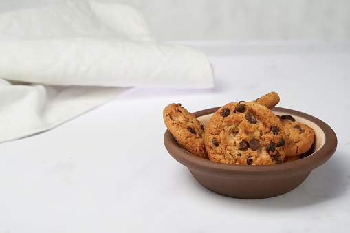 Chip chocolate cookies on a clay dish with white background