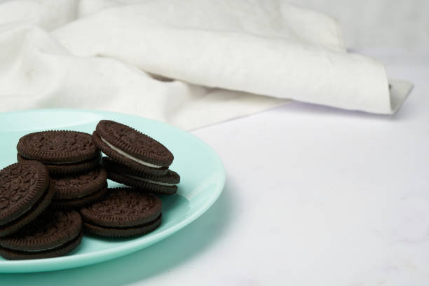 Cream filled chocolate cookies on a light blue dish with white background