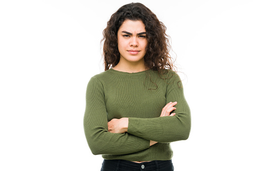 Annoyed young woman looking angrily at the camera. Hispanic woman with her arms crossed and an angry, upset expression