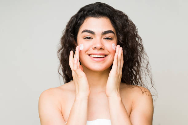 istock Young woman moisturizing her skin with face cream 1297125749