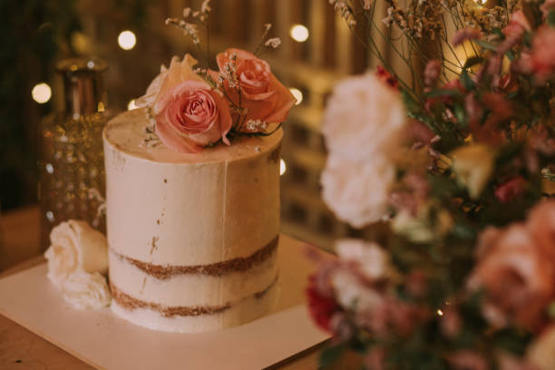 istock wedding cake decorated with pink flowers on a wooden table with background lights. 1297128111