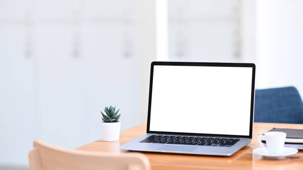 istock Minimal workplace with mock up laptop computer with white screen on wooden table. 1297128846