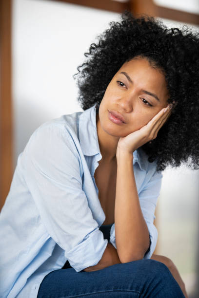 istock Sad young woman sitting indoors 1297130486