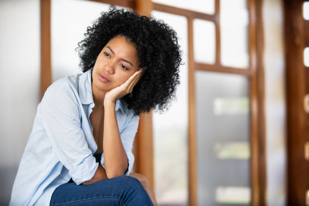 istock Sad young woman sitting indoors 1297130499