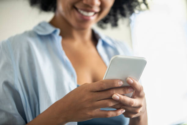 istock Smiling young woman using smartphone at home 1297130504