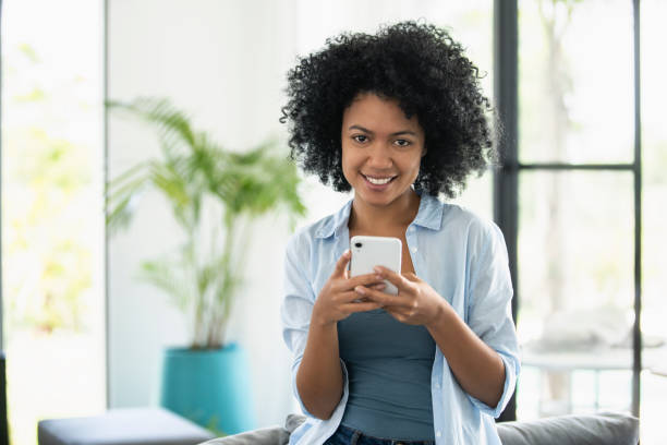 istock Smiling young woman text messaging on smartphone 1297130509