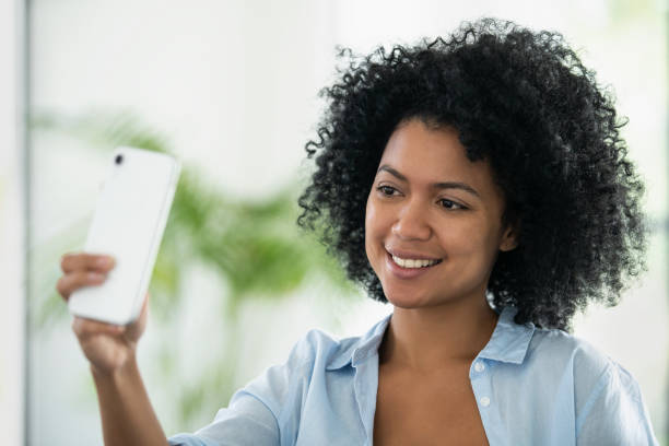 istock Smiling young woman taking selfie with smartphone 1297130527