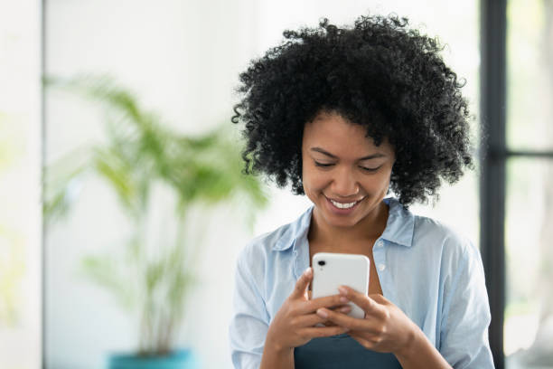 istock Smiling young woman using smartphone 1297130528