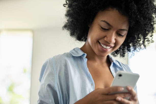 istock Smiling young woman text messaging on smartphone 1297130544