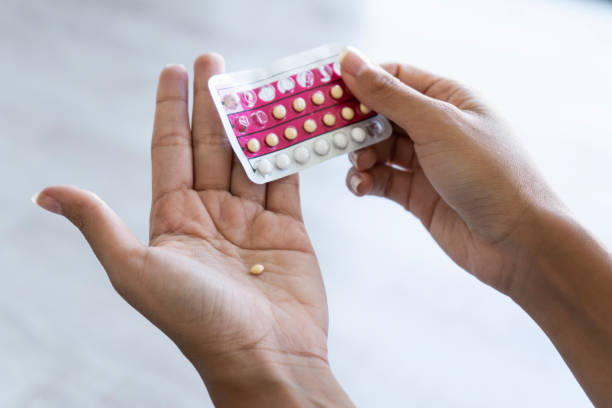 mujer sosteniendo píldoras anticonceptivas en casa - hormone fotografías e imágenes de stock